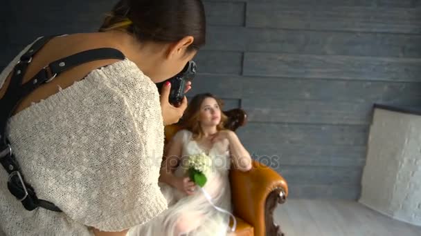 Schöne schwangere Model-Mädchen in weißem Kleid oder peignoir auf einer Kutsche posiert für Fotografen — Stockvideo