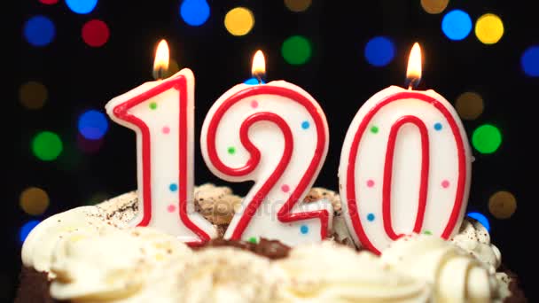 Számú 120 - százhúsz születésnapi gyertya égett - torta tetején kiolvad, a végén. Homályos színes háttérrel — Stock videók