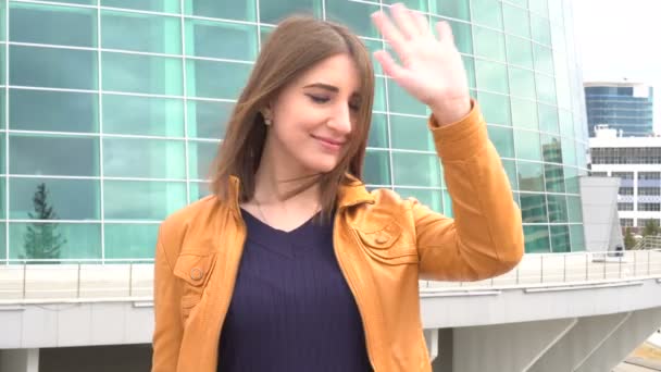 Hermosa joven, saludo, saludando mano al aire libre en la ciudad . — Vídeo de stock