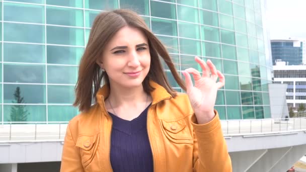 Piękna młoda kaukaski kobieta uśmiechając się znakiem ok odkryty w mieście. — Wideo stockowe