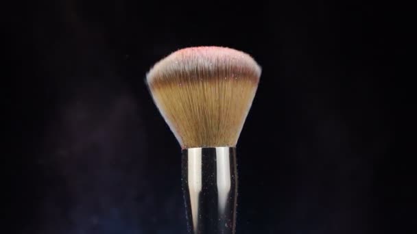 Different makeup brushes with powder flying on black background — ストック動画