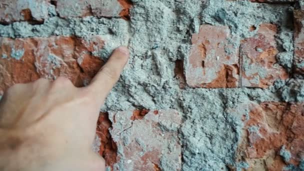 Hand points to cement in brick wall — Stockvideo