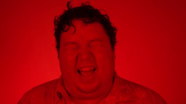 赤い照明で撮影された肖像:男は赤い背景に孤立立って笑って — ストック動画