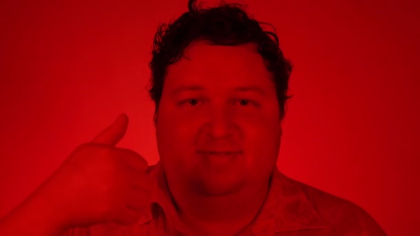 Щасливий випадковий молодий чоловік показує великий палець вгору і посміхається ізольовано на червоному освітленні — стокове відео