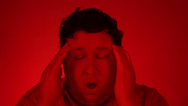 Portrait of sad man at red lighting. Fat guy getting bad news, touching head with hands. Person feeling stress — Stock Video