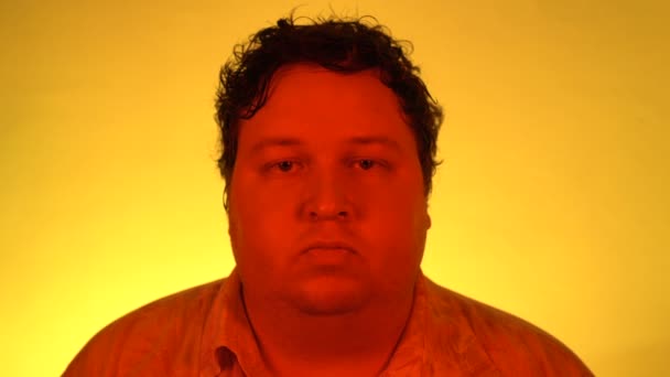 Portret poważnego mężczyzny na żółtym tle. Spokojny wyraz twarzy w czerwonym filtrze Trendy Neon Uv Light. — Wideo stockowe
