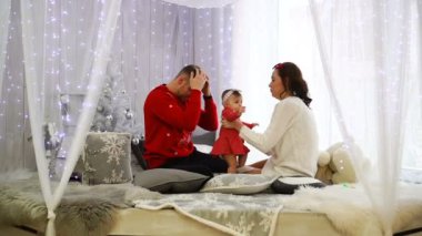 Mutlu bir aile birlikte oynuyor: anne, baba ve 1 yaşındaki kız bebek. Noel tatili