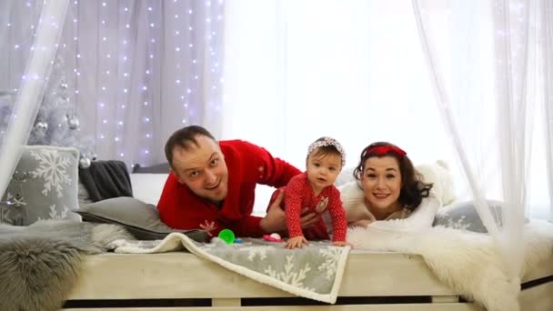 Boldog fiatal család fekszik az ágyon, mosolyog és a kamerába néz. — Stock videók