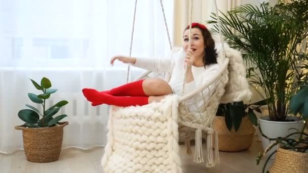Jovem mulher europeia relaxante na cadeira pendurada em sua bela casa — Vídeo de Stock