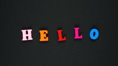 Merhaba, ahşap renkli harflerden oluşmuş bir kelime. Renkli kelimeler dönüyor. Hareketi durdur