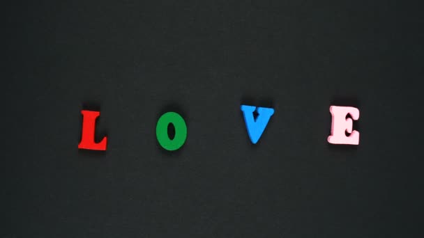 Слово любовь образовано из деревянных разноцветных букв. Красочная петля слов. Остановить анимацию — стоковое видео