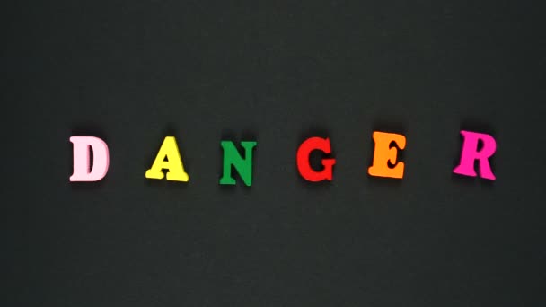 Woord gevaar gevormd door houten veelkleurige letters. Kleurrijke woorden lus. Stop bewegingsanimatie — Stockvideo