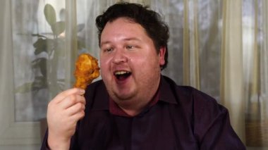 Hungry man holding a piece of fried chicken