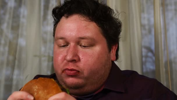 Un uomo che mangia hamburger a casa — Video Stock