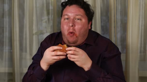 Красивий чоловік їсть бургер, кетчуп на обличчі — стокове відео