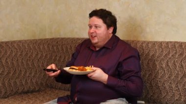 şişman adam, evde tv izlerken fast food yiyor