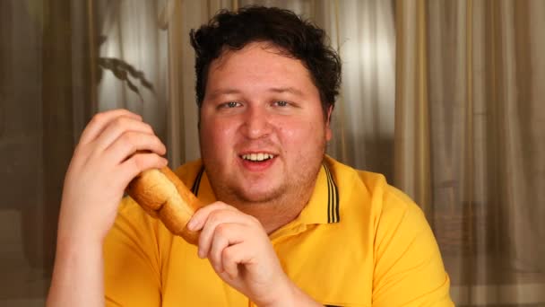 En man som håller en croissant hemma — Stockvideo