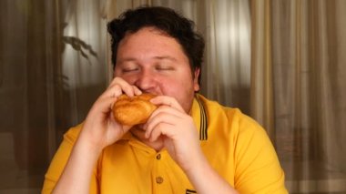 Evde kruvasan yiyen şık bir adam.