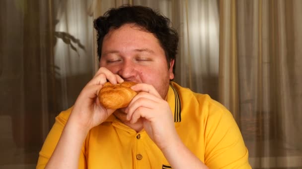 Stijlvolle man eet een croissant thuis — Stockvideo