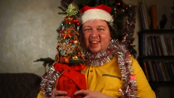 Man in kerstmuts met kleine boom — Stockvideo