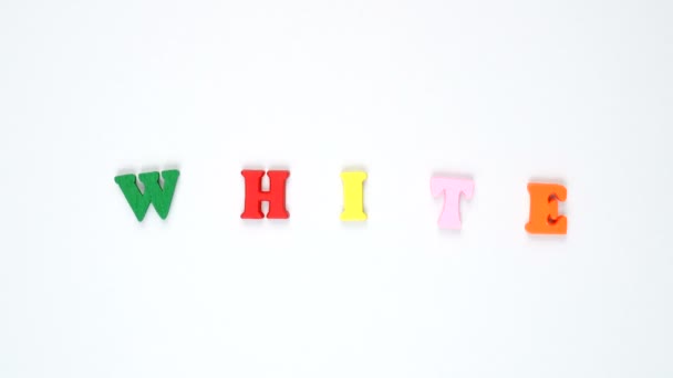 Слово "белый" образовано из деревянных разноцветных букв. Красочный цикл слов . — стоковое видео