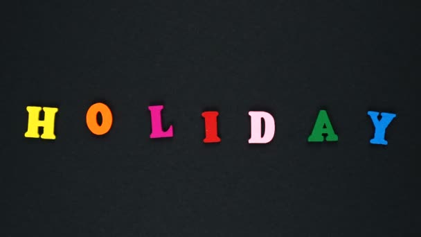 Palabra "día de fiesta" formada por letras multicolores de madera. Lazo de palabras coloridas . — Vídeo de stock
