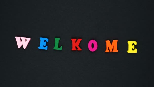Mot "bienvenue" avec erreur formé de lettres multicolores en bois. Boucle de mots colorés . — Video