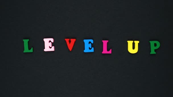 Word "level up" formed of wooden multicolored letters. Colorful words loop. — 图库视频影像