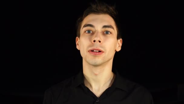 Blauäugiger Mann macht eine Schweigegegeste, schwarzer Hintergrund — Stockvideo