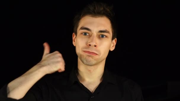 Modrooký muž v černém ukazující palec nahoru na černém pozadí — Stock video