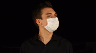 Tıbbi maskeli genç adam hayır diyor ve başını siyah arka planda sallıyor..
