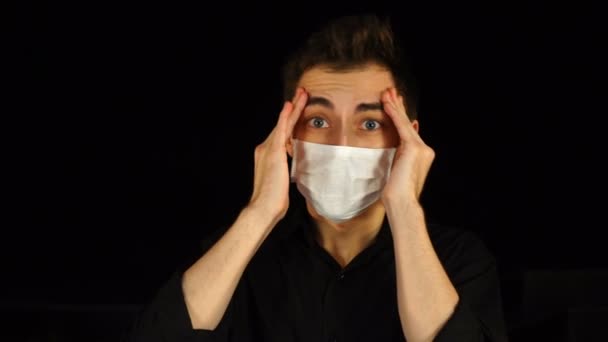 Hombre con máscara médica con temperatura, dolor de cabeza o estrés, aislado en negro — Vídeo de stock