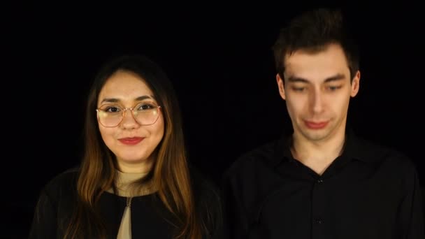 Unga par i svart säger ja och nickar med huvudet på svart bakgrund — Stockvideo