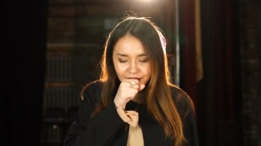 Grip onu etkiliyor. Öksüren genç bir kadın eliyle ağzını kapatıyor.