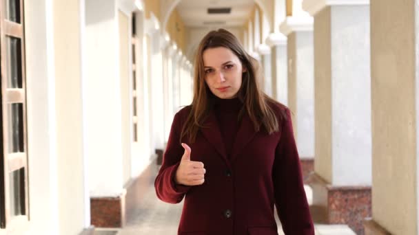 Attractive girl showing thumb up at camera, on the city street background — Stock Video