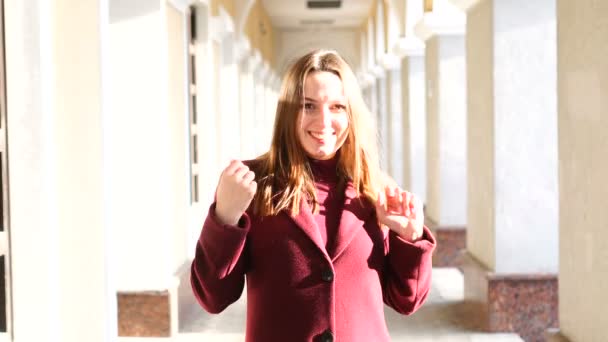 Portret van een jonge vrouw die een jas draagt die totale blijdschap en vreugde uitdrukt terwijl ze zich als winnaar of gelukkig meisje gedraagt — Stockvideo