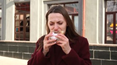 Şehirli bir caddede zevkle yemek yiyen çekici bir kız.