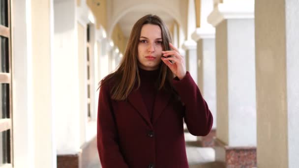 Chica atractiva mirando a la cámara, en el fondo de la calle de la ciudad — Vídeos de Stock