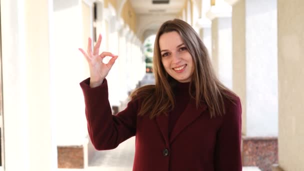 Attractive girl showing Ok gesture at camera, on the city street background — Stock Video