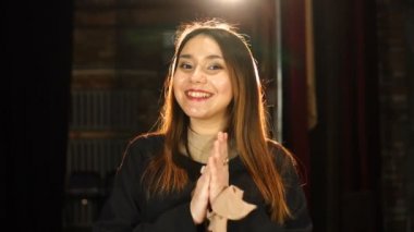 Güzel esmer kız gülümsüyor, manken ellerini çırpıyor.