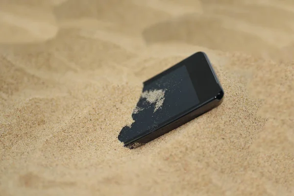 Mobilní telefon v písku. — Stock fotografie
