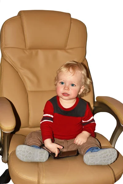 Mały chłopak siedzi w wielkim fotelu. — Zdjęcie stockowe