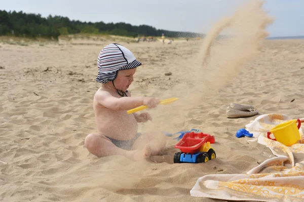 Dítě hraje na písku u moře. — Stock fotografie
