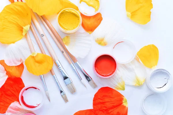 Çiçek guaş ile beyaz masaya bırakır..