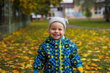 Çocuk sarı sonbahar ile yeşil çimenlerin üzerinde bırakır.