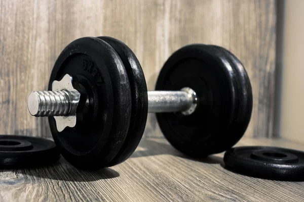 Black dumbbell on wooden background. — Stock Photo, Image