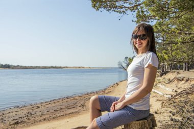 Deniz kıyısında yatan gülümseyen genç kadının portresi