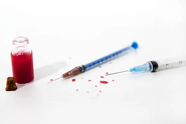 Medicinspruta och röda droppar från glasrör på vitt bord. Virus abstrakt foto. — Stockfoto