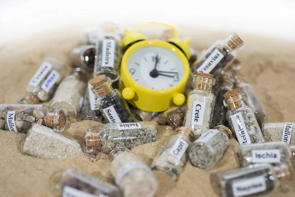 Glass test-tube with sand of different summer vacation destinations. Located in sand with clock. Vacation time abstract photo. — 스톡 사진