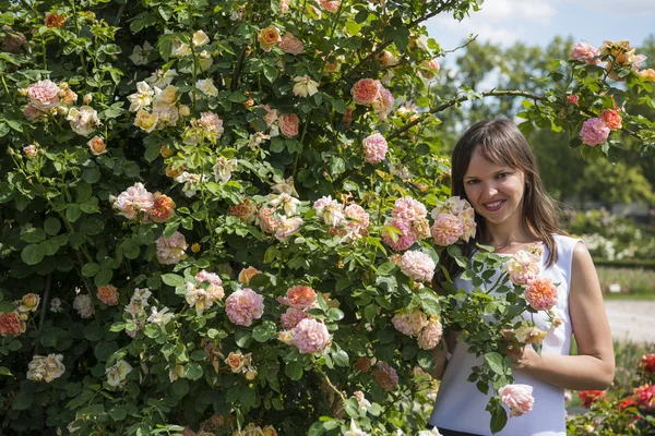 Τριαντάφυλλα κήπο και χαμογελαστή ευτυχισμένη γυναίκα την ηλιόλουστη μέρα του καλοκαιριού. — Φωτογραφία Αρχείου